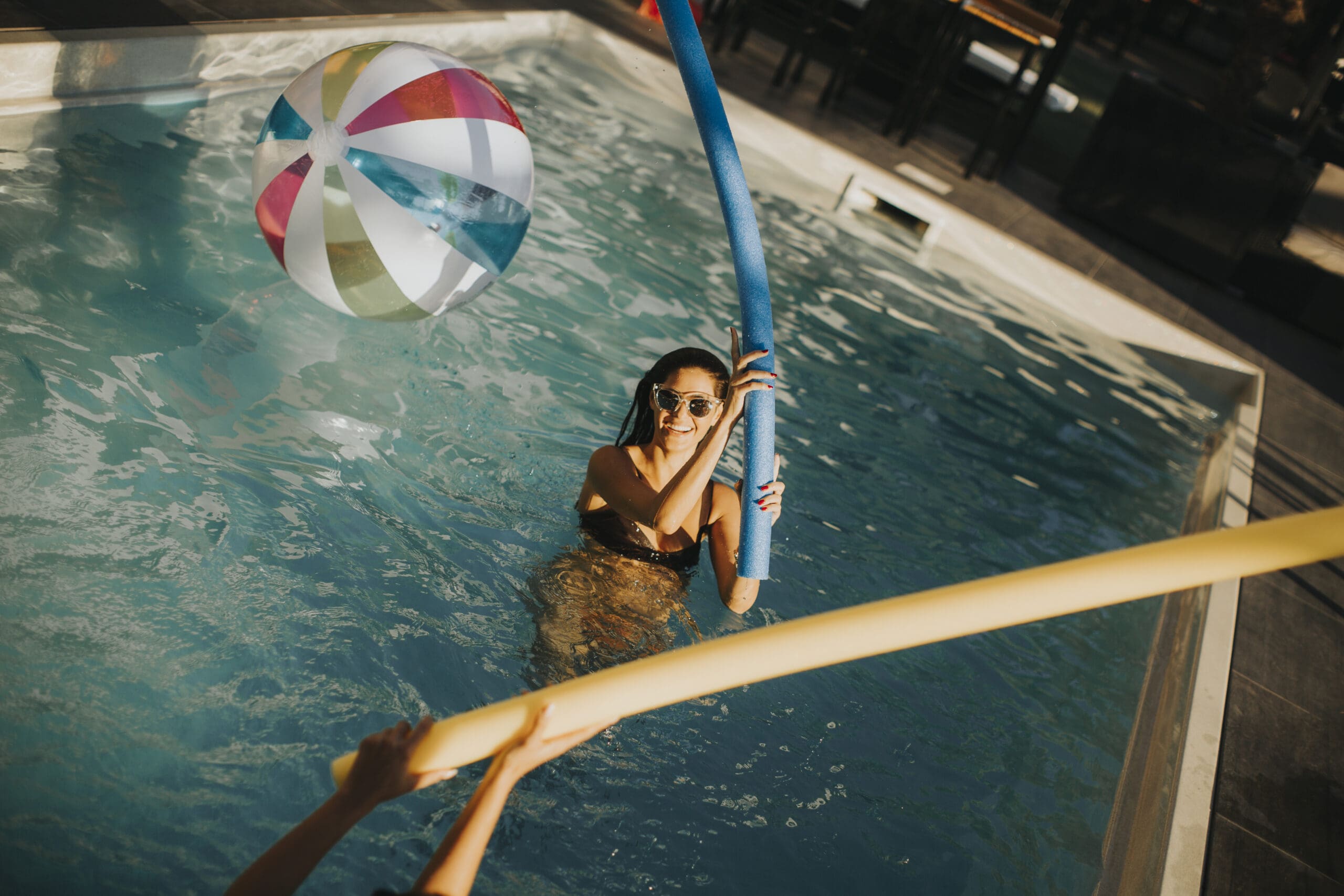 Young women having fun with swimming pool noodles